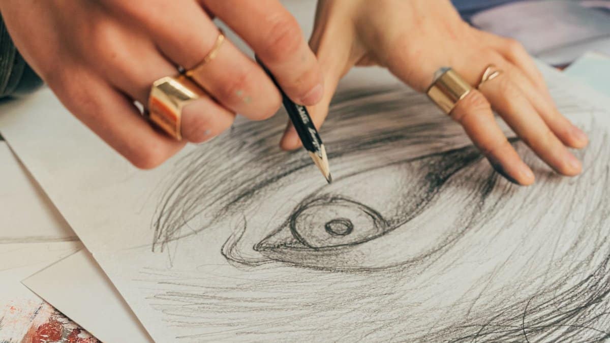 Artist's hand sketching an eye in pencil: every lash set at Envious Lashes starts as a design